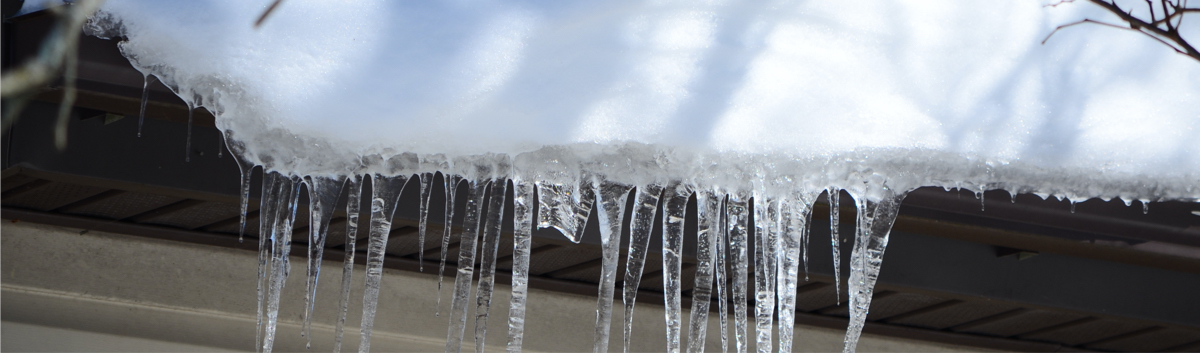 Gouttières obstruées par la glace et la neige, montrant comment l’accumulation peut causer des infiltrations d’eau dans la toiture en hiver.  